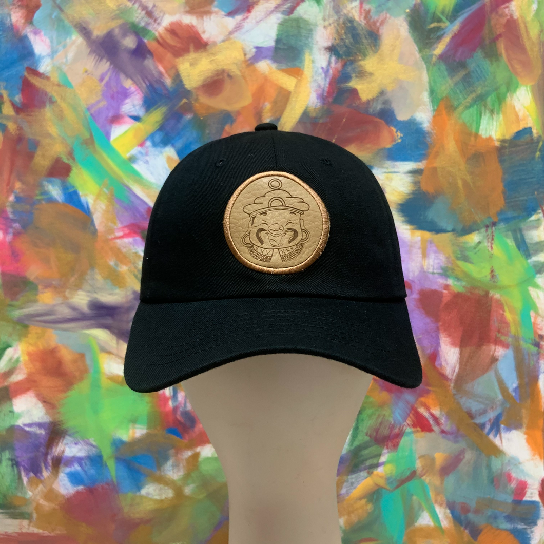 black strapback hat with a light tan leather patch of a genie.