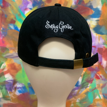 Load image into Gallery viewer, black strapback dad hat with a design under cap